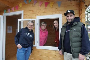 Vier Menschen und ein Spielhaus, zwei schauen zum Fenster hinaus, zwei stehen davor
