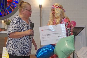Eine Frau hält ein Mikro in der Hand, eine zweite einen übergroßen symbolischen Scheck